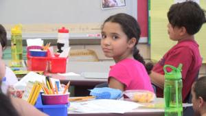 Image of an elementary school girl in a classroom, looking at the camera.